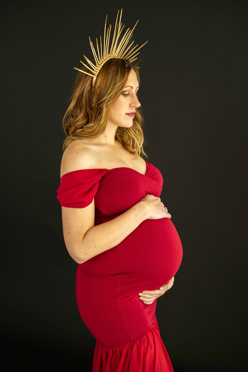 Woman in red dress holding belly maternity boudoir Denver